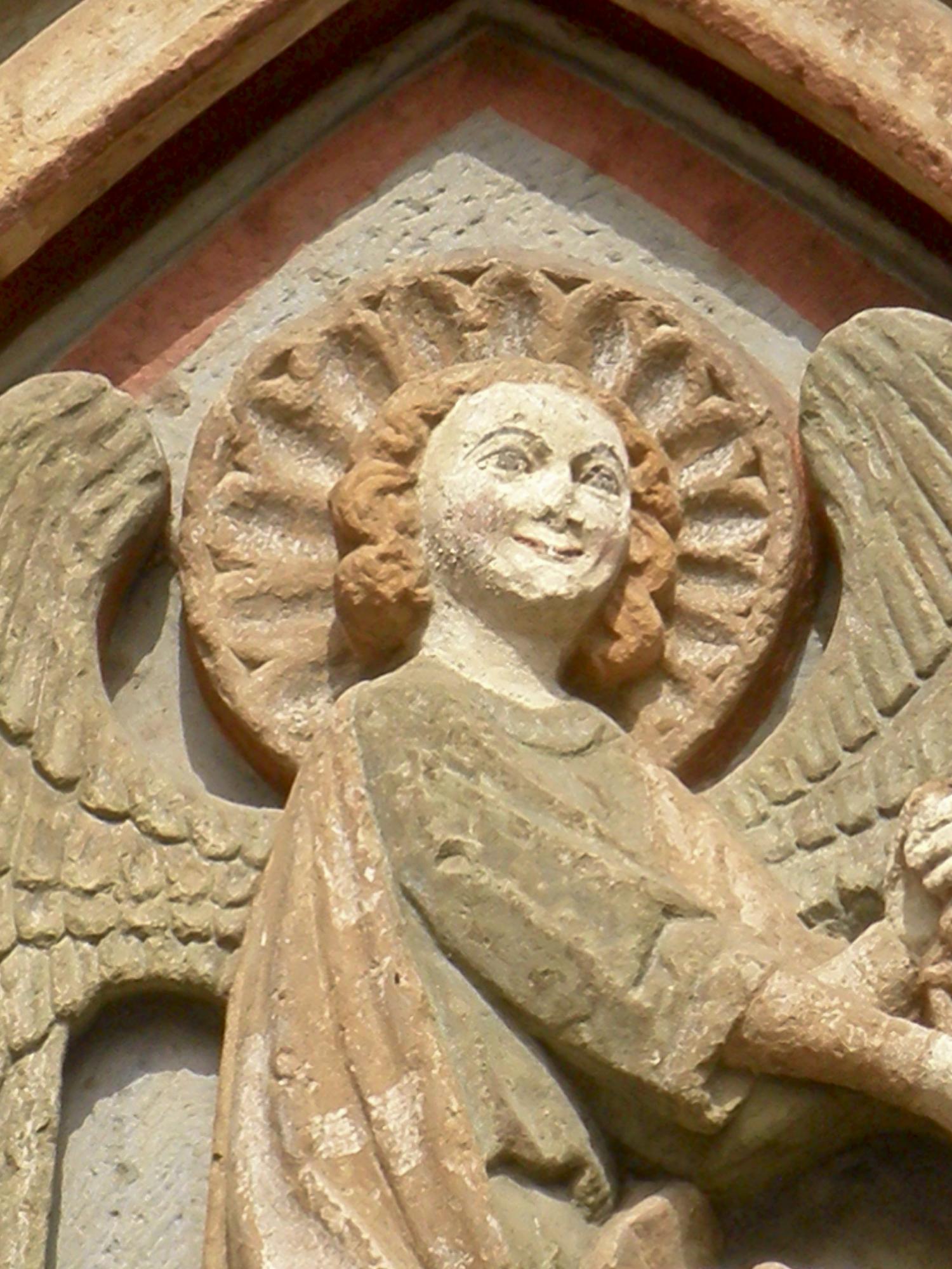 Steinrelief eines Engels mit Heiligenschein an einer Kirchenfassade