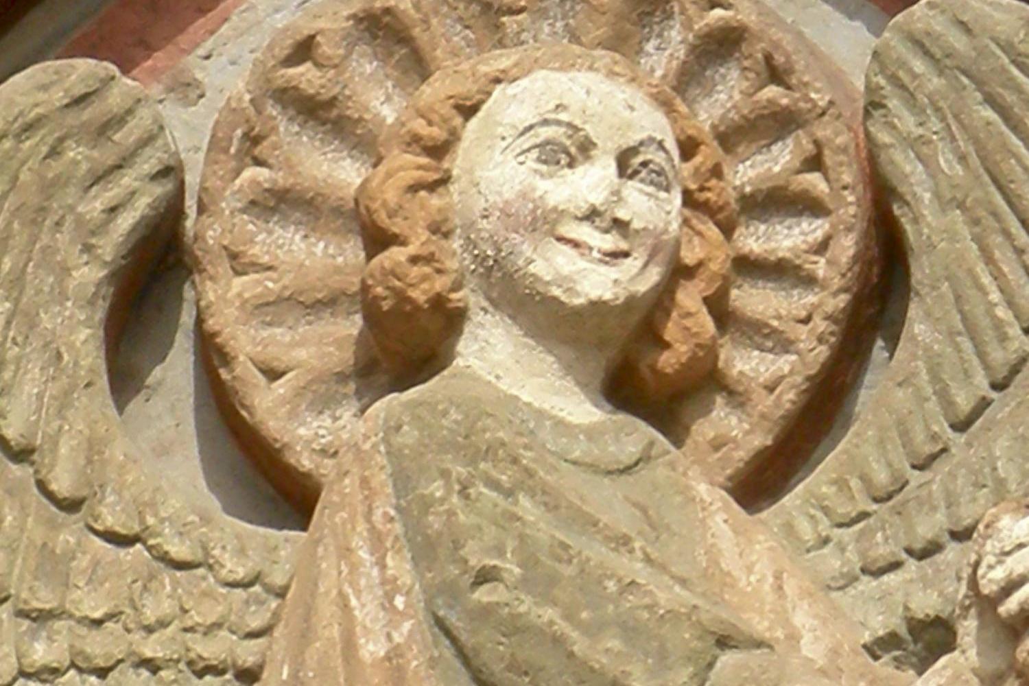 Steinrelief eines Engels mit Heiligenschein an einer Kirchenfassade